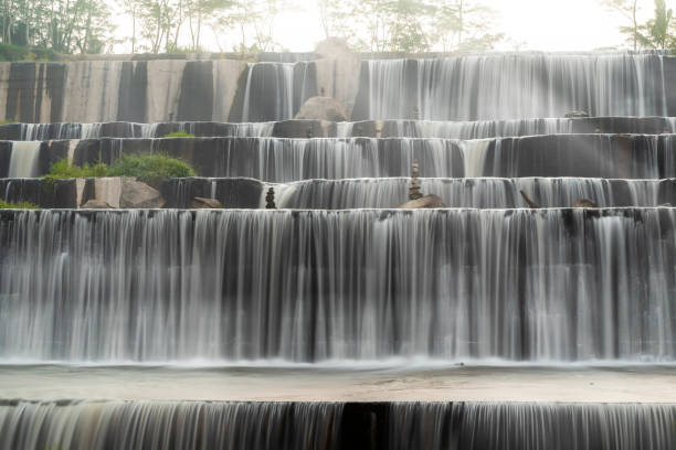 A waterfall with a lot of water and rocks in Grojogan Watu Purbo, Yogyakarta, Indonesia