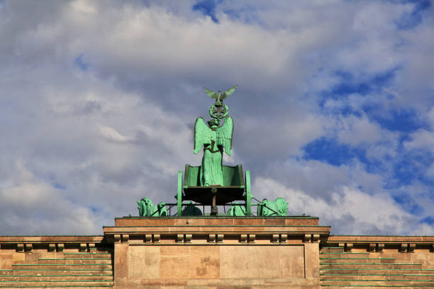 A low angle view looking up towards the top of the Brandenburg Gate from between two columns, on a bright and sunny day in Berlin, Germany.