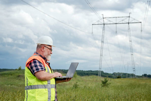 istock Electrical engineer working with a laptop in front of a high voltage tower 2156601095