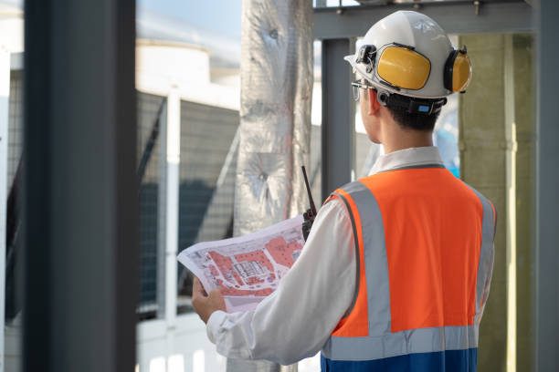 istock Back Asia male engineer in protective workwear is performing a conducts system check with use paper work at rooftop building 2156604482