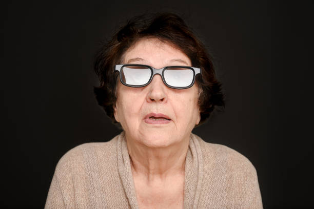 Senior lady looking up watch 3d movie on a black background. Portrait of an elderly woman wearing glasses watching 3D movies in a home cinema system. Selective focus