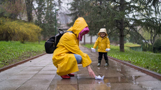 istock It's springtime. A small child in rubber boots jumps through puddles, plays and launches paper boats on the water. 2156606124