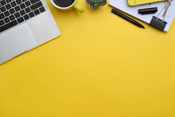 istock Top view of laptop, coffee cup and documents on yellow background with copy space 2156607380