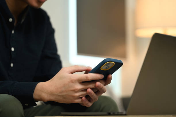 istock Male freelancer working with laptop and using mobile phone on couch in living room 2156607468
