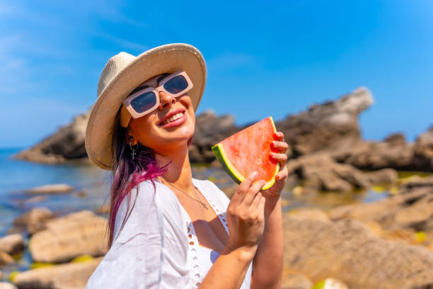 istock A woman is holding a watermelon slice in her hand while wearing a straw hat 2156610423