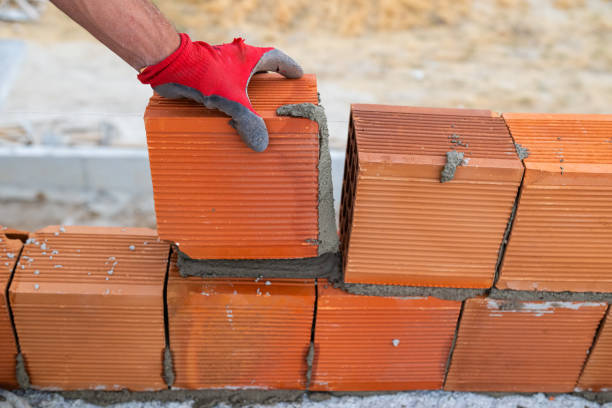 istock Worker builds a brick wall for house construction. Worker building a brick wall using mortar. Close-up of bricklayer placing bricks at construction site. Labourer with bricks. 2156612491