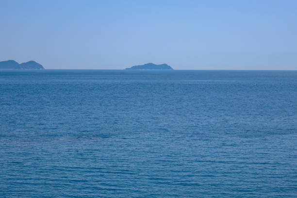 Bandoko Garden Scenery of Japan horizontal. A calming seascape. Clear blue ocean waves gently roll towards the shore with a clear blue sky.