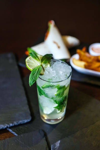 A glass with a green drink is placed next to a plate of crispy fries.