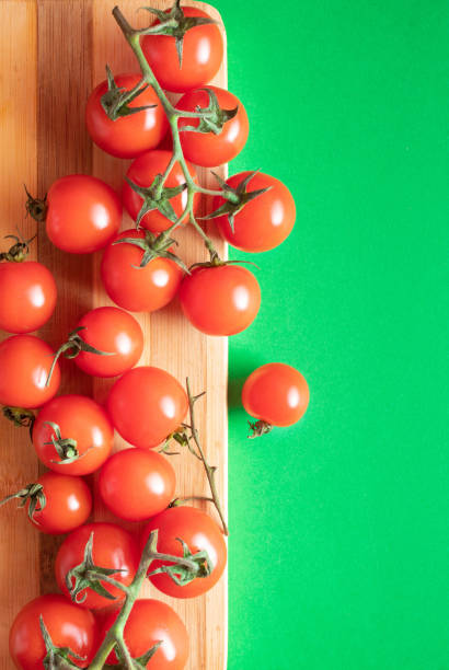 istock Cherry tomatoes on wooden board on green background. Copy space 2156617548