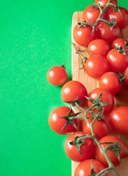 istock Cherry tomatoes on wooden board on green background. Copy space 2156617556