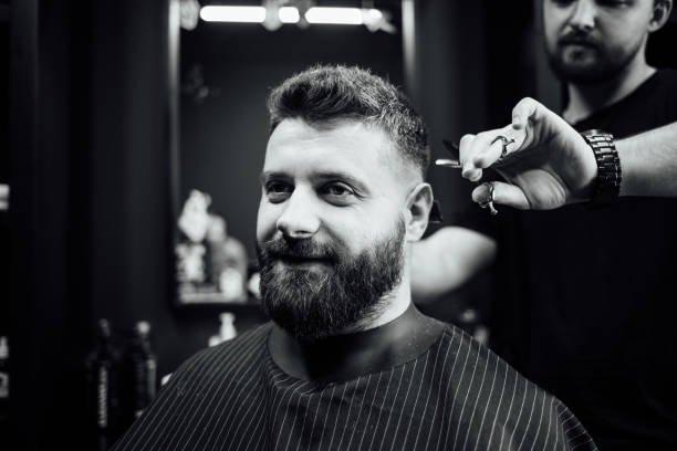 istock A man with a beard is getting his hair cut by a barber 2156620438