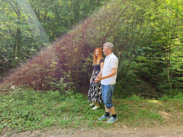Couple in love enjoy beautiful summer day in the forest. Lens flares are visible.