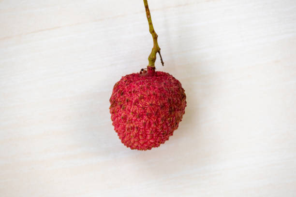 A fresh lychee (Litchi chinensis) on light wooden background