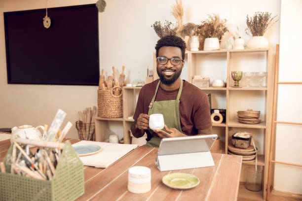 istock Dark-skinned sculptor demonstrating a new cup to the audience on online tutorial 2156628327
