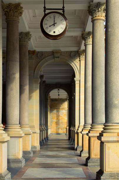 Scenic landscape view Mill colonnade from marble with vintage clock in the ceiling. Famous touristic place and romantic travel destination in Karlovy Vary, Czech Republic.