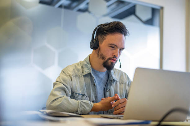 istock Young man wearing headset while participating in video call at inclusive office 2156646535