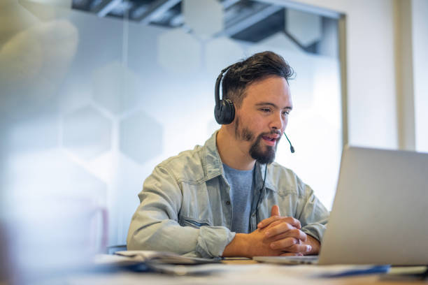 Young man wearing headset while participating in video call at inclusive office