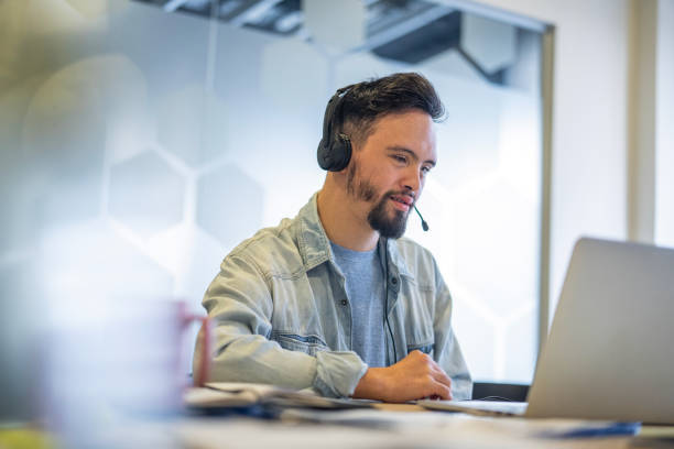istock Young man wearing headset while participating in video call at inclusive office 2156646721