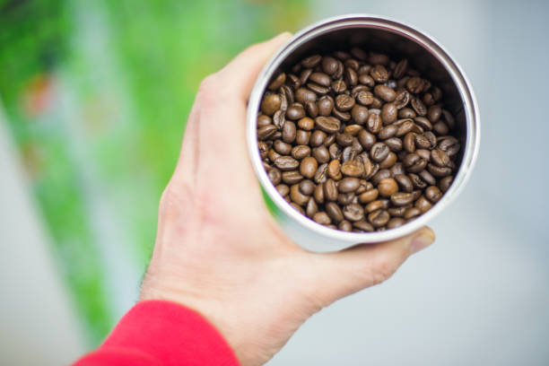 A hand holds a container filled with Arabica coffee beans in the city of Seville, Spain.