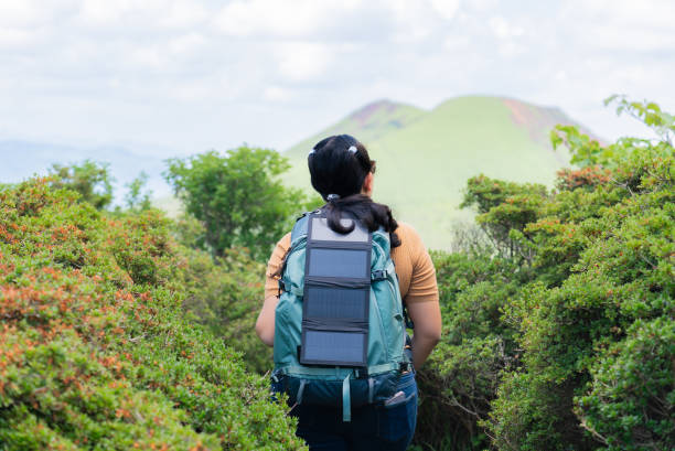 istock An Asian mid-adult woman using solar cell on her backpack to power her small devices during trekking in the forest, on the go for camping 2156667555