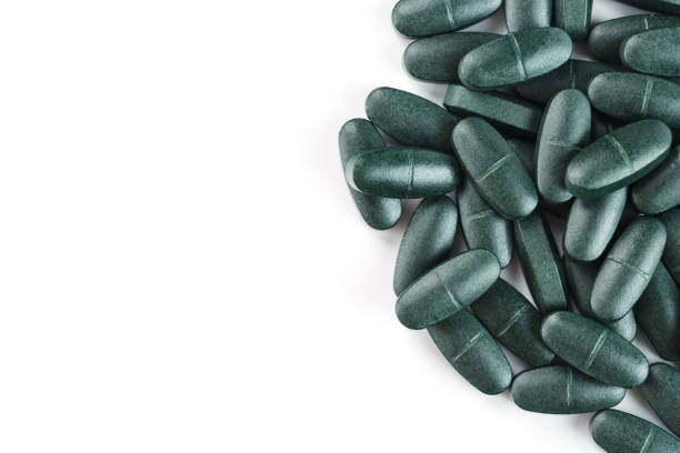 green pills and  a pill bottel on  a wood background