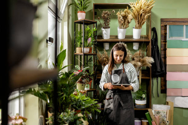 istock Beautiful Woman Using Digital Tablet in Flower Shop 2156676589