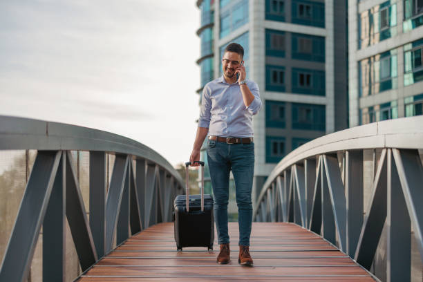 istock Businessman on phone with suitcase on bridge 2156677161