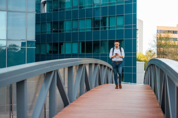 Man crossing bridge near office buildings