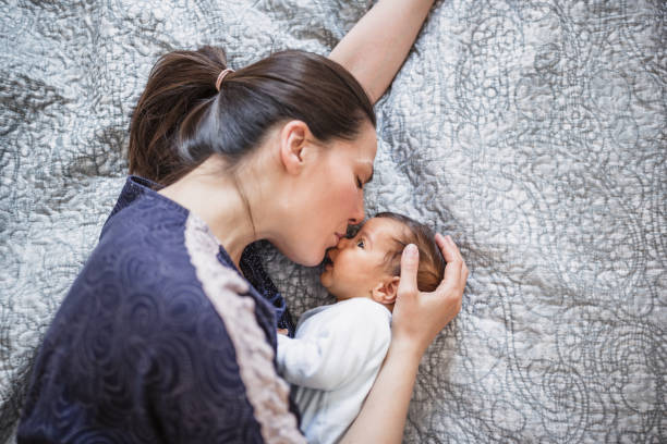 istock Mother Kissing Newborn on Bed 2156680214