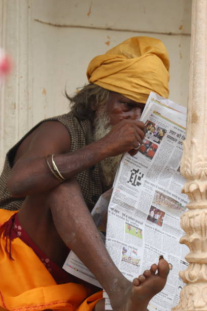 shot in pushkar town, a indian ethnicity man sitting and reading local newspaper
