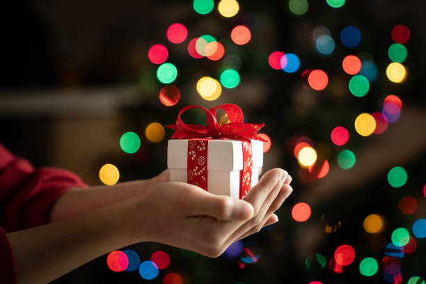 istock Hand holding gift in front of chirstmas tree 2156682319