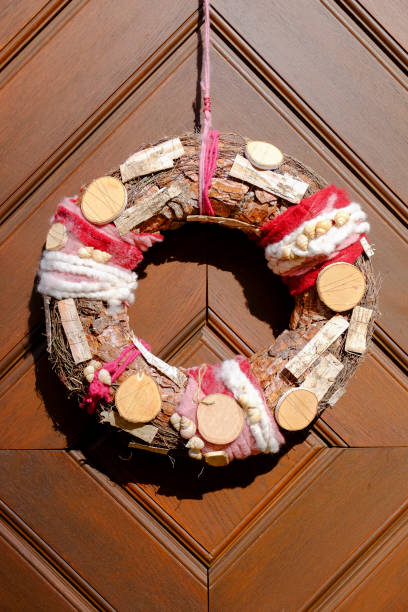 Door wreath with natural materials such as wooden discs, tree bark and snail shells