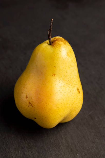 ripe pear on a black slate, ripe green and yellow pear on a board