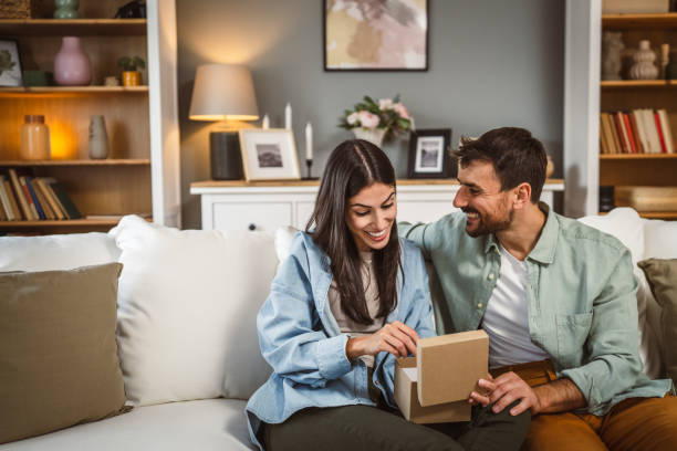 istock Girlfriend open her birthday present from her boyfriend at home 2156686691