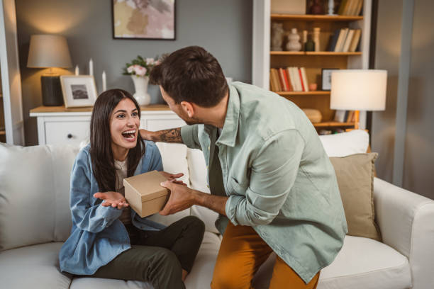 istock Girlfriend open her birthday present from her boyfriend at home 2156687128