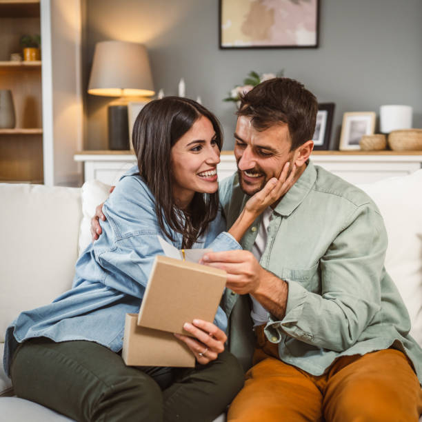 istock Girlfriend open her birthday present from her boyfriend at home 2156687514