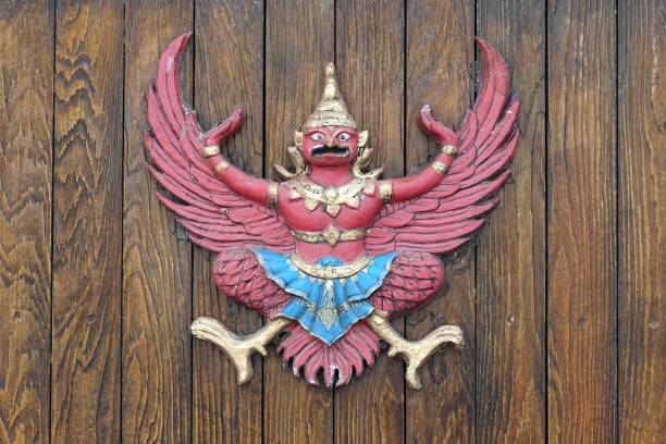 A vintage garuda statue on wooden fence background.