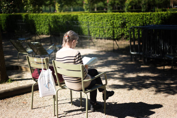 Paris, France: A woman reads a book on a sunny day in a corner of the Luxembourg Gardens.