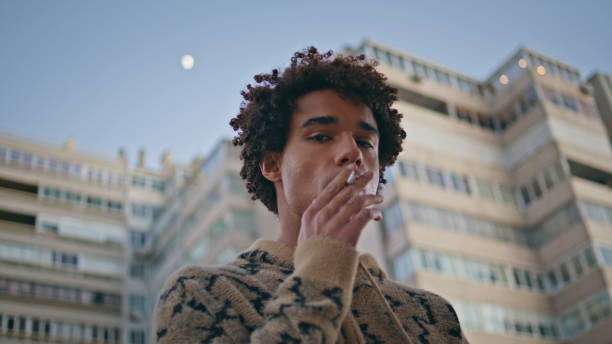 istock Closeup guy smoking thoughtfully in city. Curly-haired young hipster addicted 2156690167