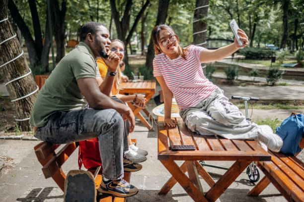 istock Friends having fun outdoors enjoying in city park taking a selfie using mobile phone 2156695738