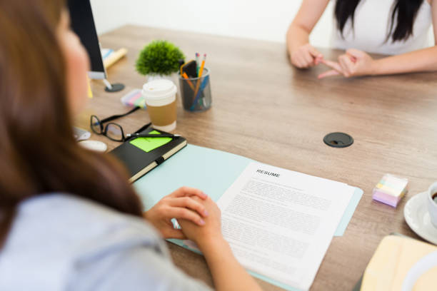 Close-up view of a job interview setting with resume on table, candidate and recruiter engaged in a professional conversation