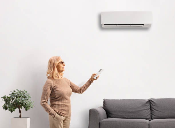 istock Middle aged woman putting on an air conditioner mounted on a wall 2156708662