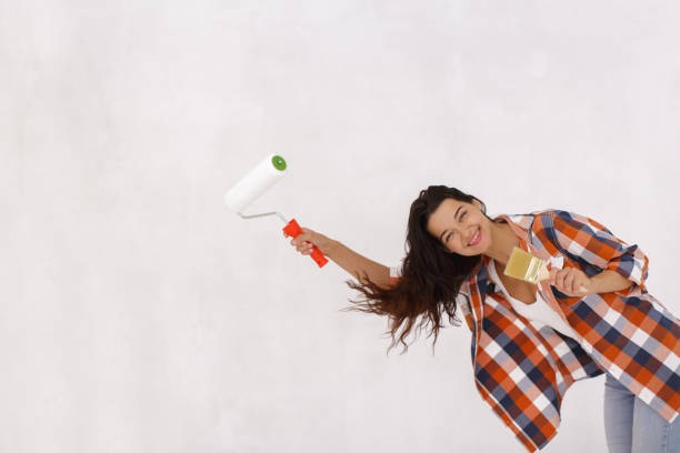 istock Smiling Woman with Paint Roller and Brush During Fun Home Renovation 2156720439
