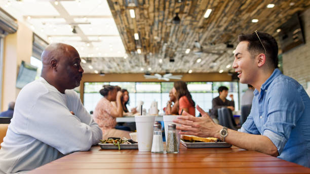 istock Young Man Talking to Mature Man at Lunch in Restaurant 2156725632