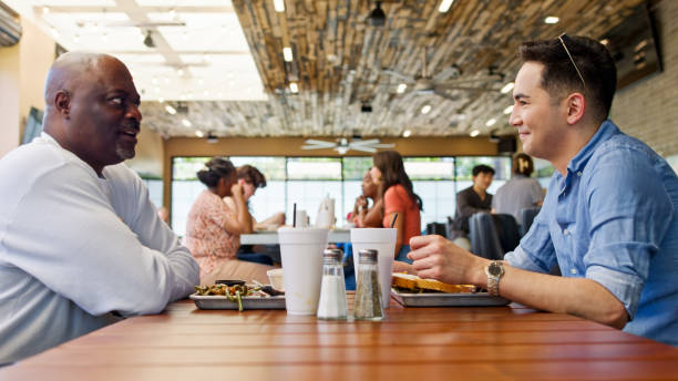 istock Mature Man Talking to Young Man at Lunch in Restaurant 2156725633