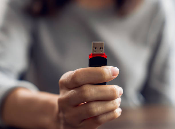istock Hand holding usb flash drive with connecting to laptop at wooden table 2156726578