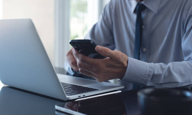 istock Businessman using mobile phone searching the information and working on laptop computer at office. Business man online working and using smartphone surfing the internet, business concept 2156726647