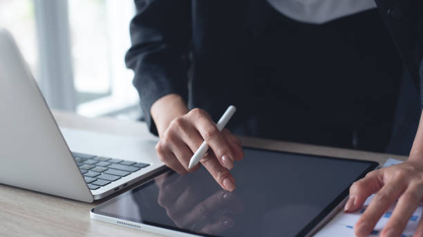 istock Businesswoman hand with stylus pen using digital tablet, proofing e-document, financial report on office table. Business woman, project manager planning and working on computer, business technology 2156727494