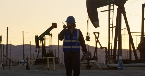 istock Indian Worker Using Radio in an Oilfield at Sunset 2156728751