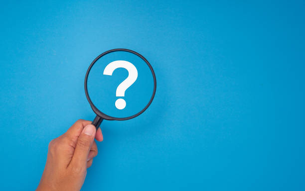 Hand holding a magnifying glass with a white question mark on a blue background.